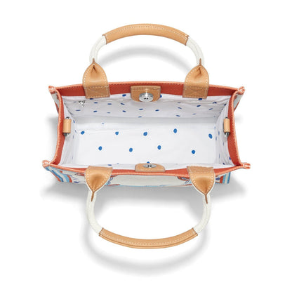 Brighton handbag interior view showing white blue polka dot lining, tan leather trim, and silver-tone snap closure on a white background