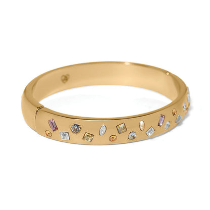 Brighton gold-plated bangle bracelet with scattered multicolored crystals in assorted shapes and sizes on a white background
