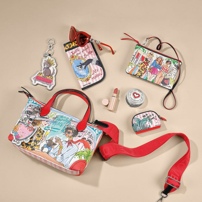 Brighton handbag with illustrated Beverly Hills print and red strap, styled with sunglasses and other accessories on a neutral background