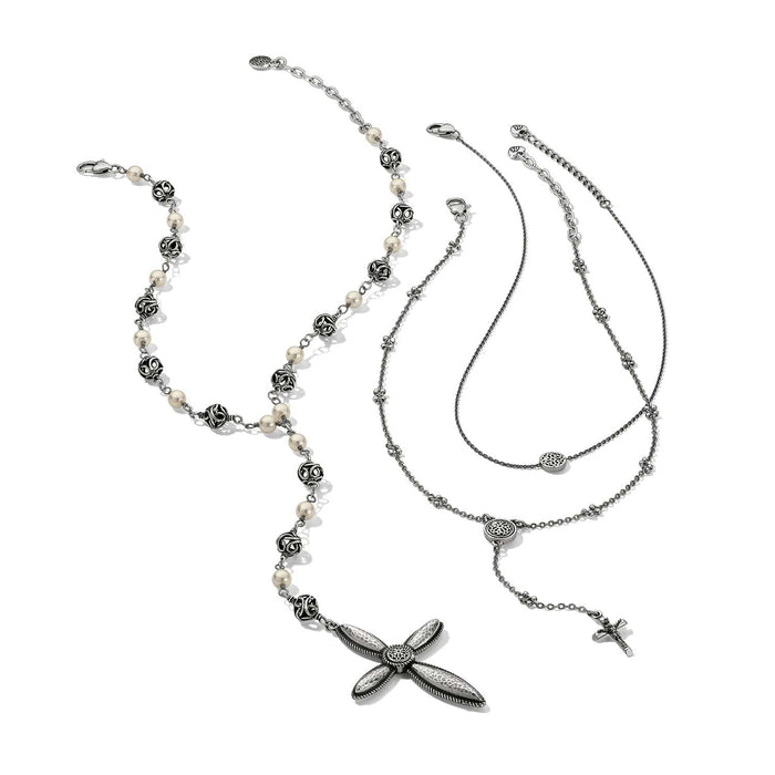 Brighton necklaces styled with a beaded pearl strand and silver-plated cross pendants on a white background