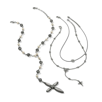Brighton necklaces styled with a beaded pearl strand and silver-plated cross pendants on a white background