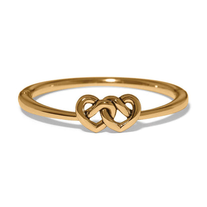 Brighton ring with gold-plated band and two interlocking heart motifs at the center on a white background