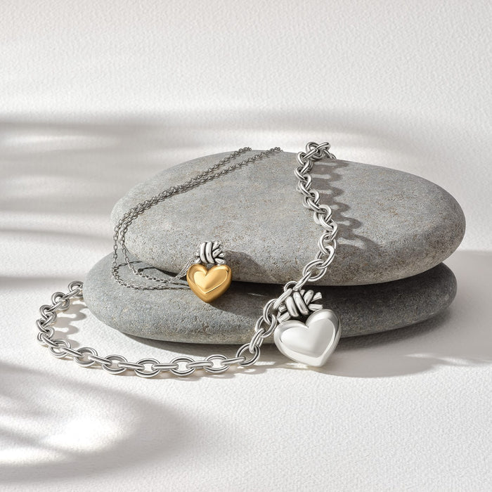 Brighton heart charms in silver-plated and gold-tone finishes styled with chains on smooth gray stones