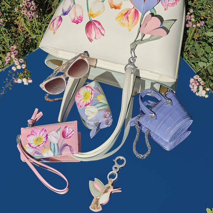 Brighton leather handbag with floral tulip print, styled with sunglasses and other accessories on a blue background
