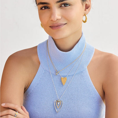 Model wearing layered Brighton two-tone heart pendant necklaces with crystal accents and coordinating Brighton accessories