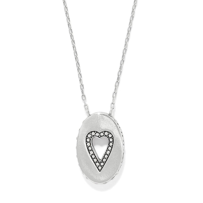 Brighton pendant necklace with silver-plated oval medallion featuring cut-out heart outlined in crystals on a white background