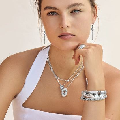 Model wearing Brighton silver-plated heart pendant necklaces with coordinating Brighton accessories including drop earrings, ring, and bracelets