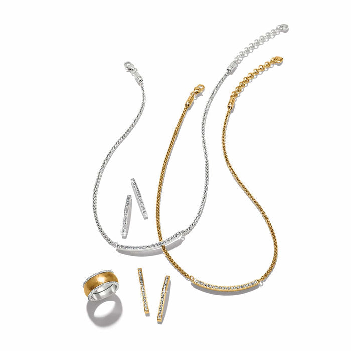Brighton jewelry set styled with silver and gold-plated necklaces, crystal bar earrings, and a ring on white