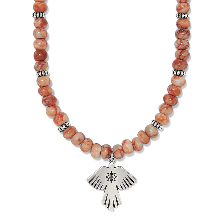 Brighton beaded necklace with orange marbled stone beads, silver-plated spacers, and thunderbird pendant on a white background