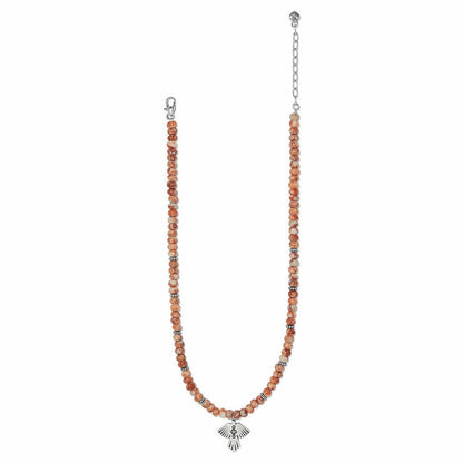 Brighton beaded necklace with orange marbled beads, silver-plated spacers, and thunderbird pendant on a white background