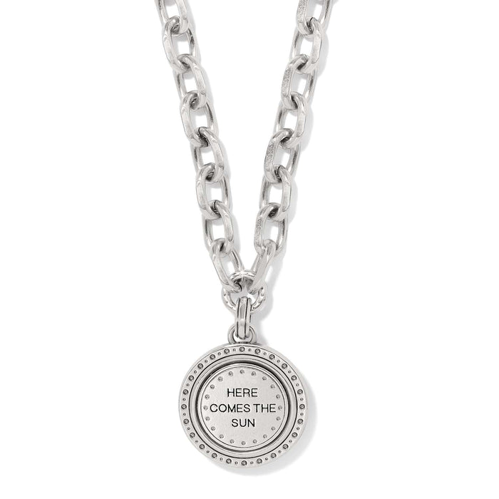 Brighton pendant necklace with chunky silver-tone chain and round medallion engraved Here Comes The Sun on a white background