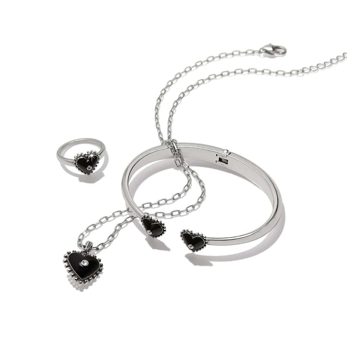 Brighton silver-plated jewelry set with black enamel heart pendant necklace, bangle, and ring with crystal accents on a white background