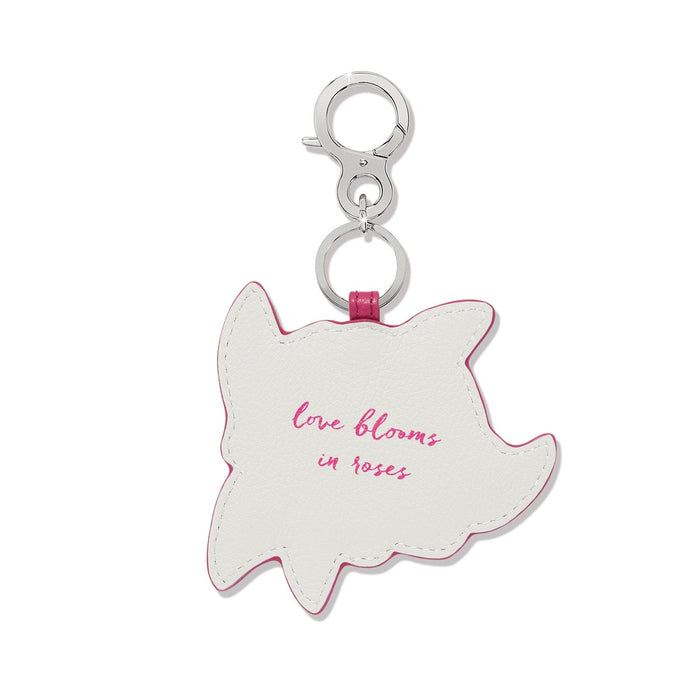 Brighton leather bag charm shown from the back with pink trim and "love blooms in roses" script on a white background