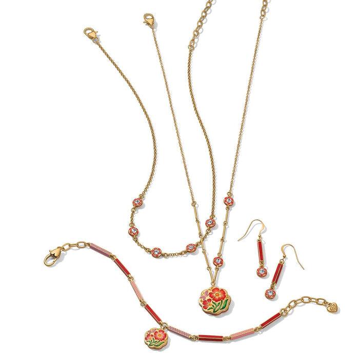 Brighton gold-plated jewelry set styled with floral enamel pendants, crystal accents, and red enamel earrings on white background