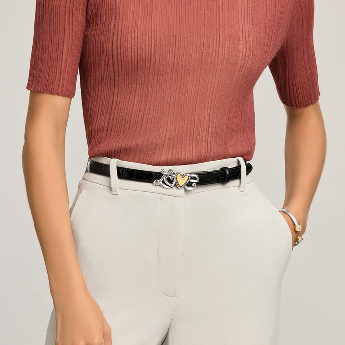 Model wearing a Brighton black leather belt with silver-tone scroll buckle and gold heart center accent