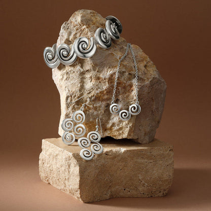Brighton silver-plated jewelry set styled with spiral motif cuff, necklace, and earrings on stacked stone blocks